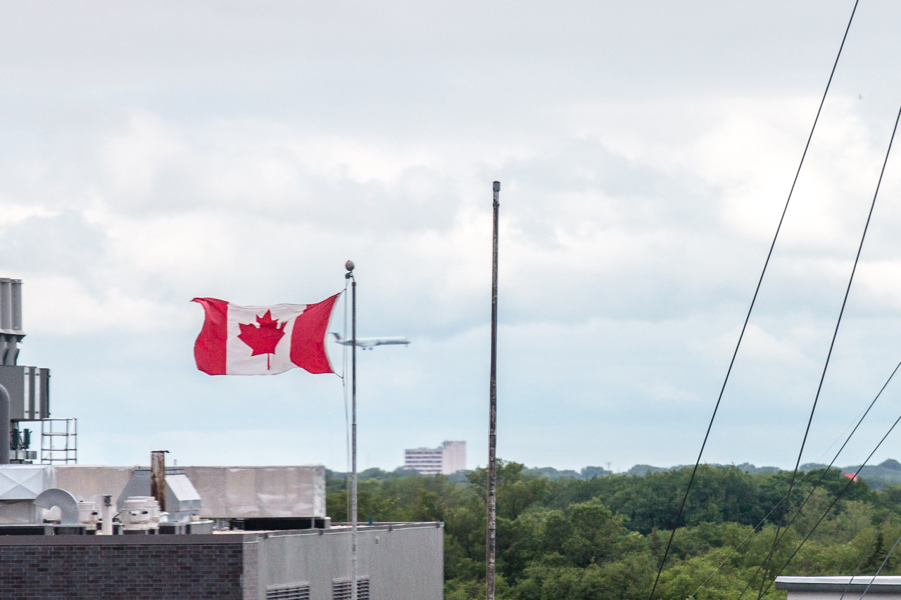 In Background Plane Passes Canadian Flag 
