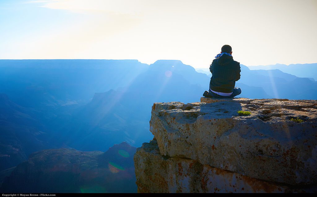 Young Man Meditatiing on cliff overlooking valley